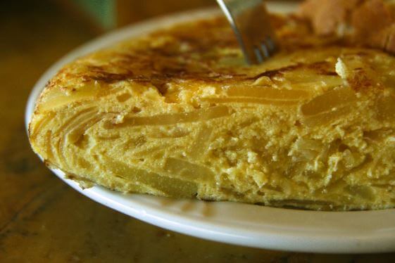 A thick slice of Spanish potato omelette on a white plate
