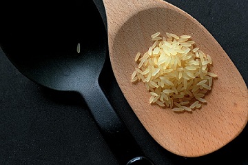 Uncooked long-grain rice in a wooden spoon